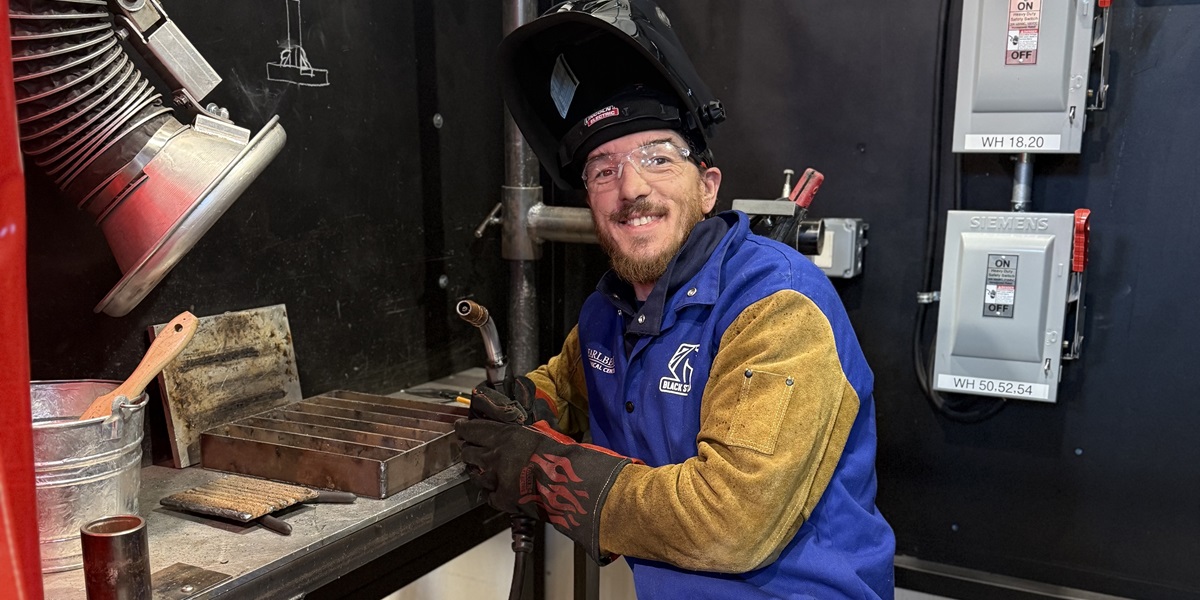 Indie in the welding lab next to welding equipment