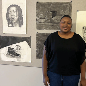 Student posing with their work at portfolio night.