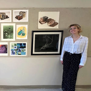Student posing with their work at portfolio night.