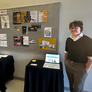 Student posing with their work at portfolio night.