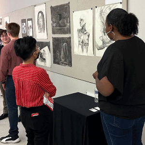 Person looking at a student's art display in a hallway with other displays.