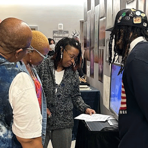 Person looking at a student's art display in a hallway with other displays.