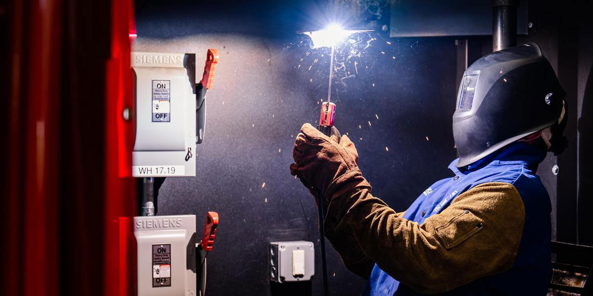 A student with a torch in a welding class.