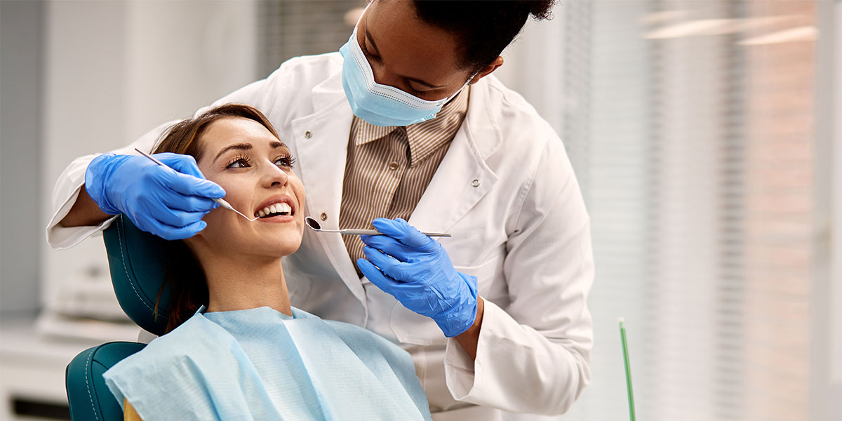 A dental hygienist looks into the mouth of a patient