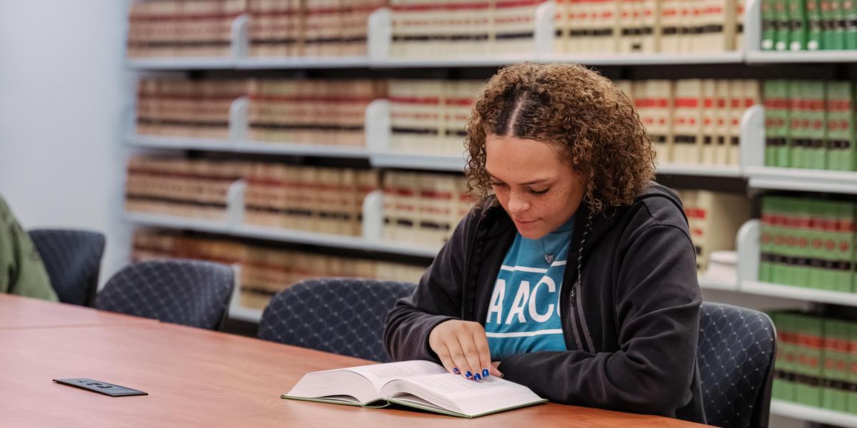 Student inside law library reading a book.