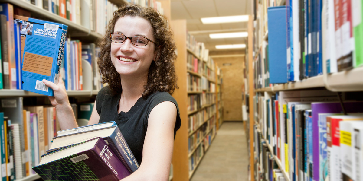 Student taking books off a library shelf.