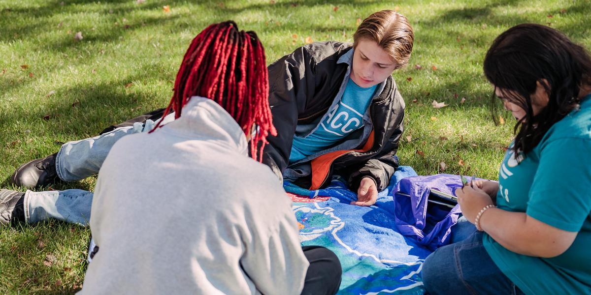 AACC students sitting outside on the grass.